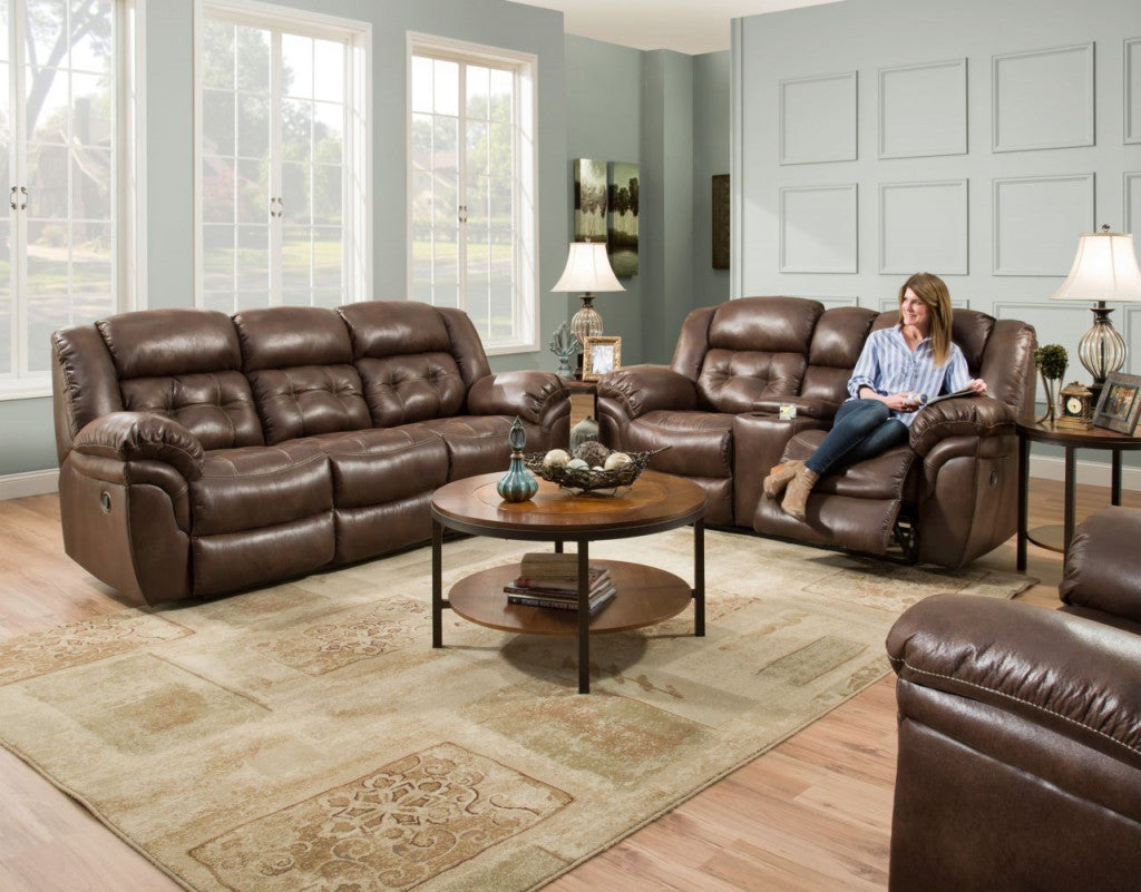 Brown leather sofa set in a living room with a woman sitting on one of the sofas.
